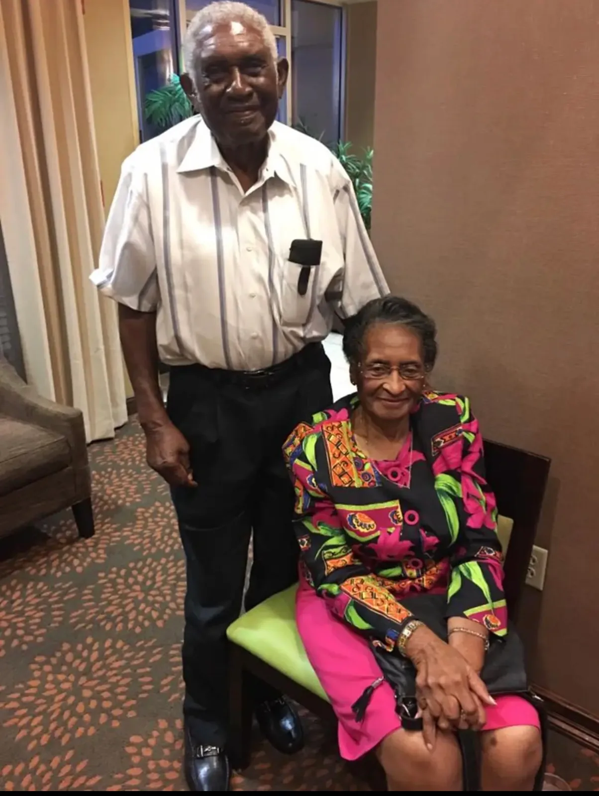 The Edwards family's Matriarch and Patriarch, the two living siblings, he standing and she seated, dressed up for a family gathering.