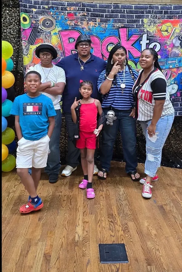 A family with two children posing at the party backdrop.