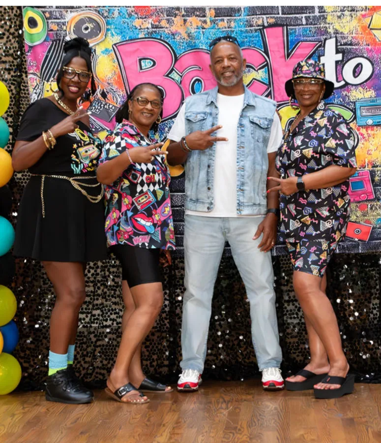 Four relatives in bold prints posing at the “Back to” party backdrop.