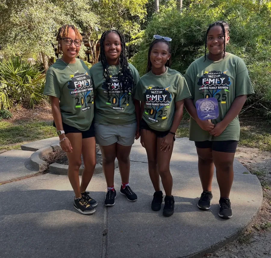Four young women in green reunion T-shirts standing together on a path.