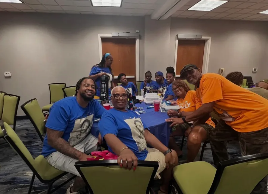Family seated around a table in blue reunion shirts.