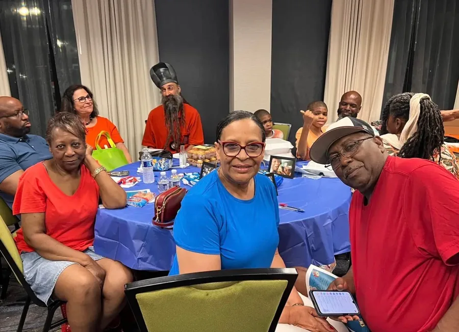Relatives smiling around a table with a blue cloth in a banquet hall.