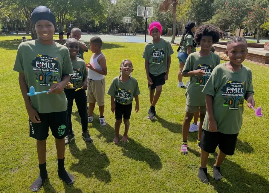 Children in green reunion T-shirts lined up on the grass.