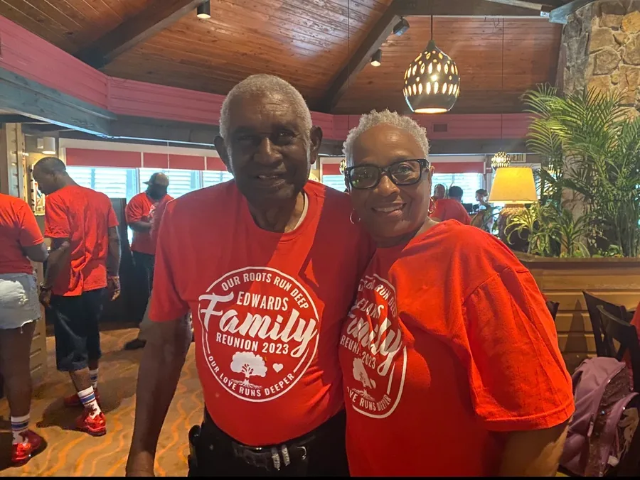 Two relatives in red Edwards Family Reunion shirts, arm in arm.