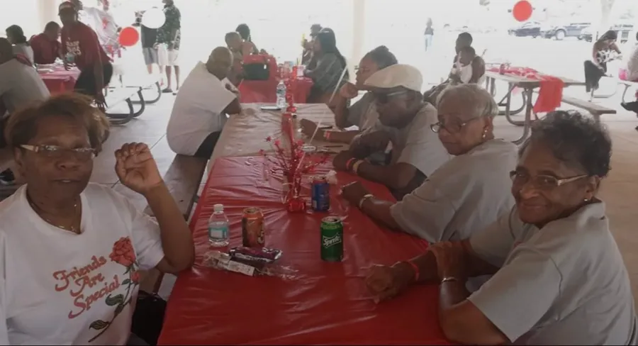 Relatives in reunion shirts sharing a long table set in red.