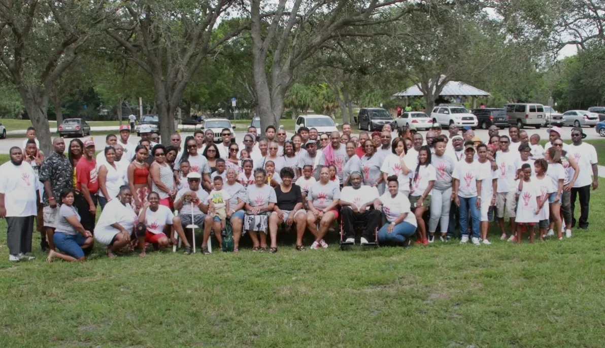 The Edwards family gathered on a park lawn in matching white reunion shirts.