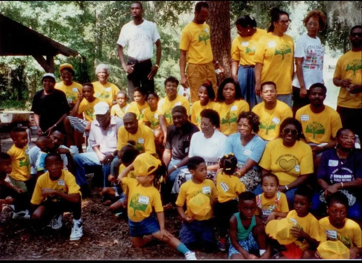 Relatives of every age in yellow reunion T-shirts under the trees.